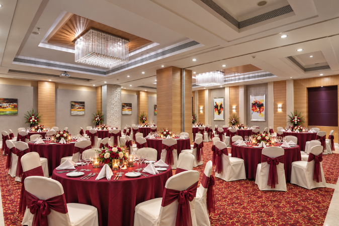 Symphony banquet hall in Nashik with round dining tables, floral 
centerpieces, elegant seating and a beautifully decorated event space